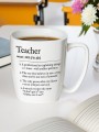 Kubek z napisem „Teacher” wypełniony kawą, postawiony na biurku obok otwartego zeszytu i bukietu kwiatów w tle.